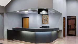 Un comptoir d’accueil au design moderne, une œuvre d’art encadrée au-dessus, et une porte sur la gauche.