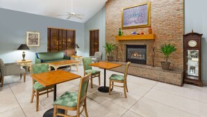 Un salon avec une cheminée en briques, un ventilateur de plafond et une horloge.