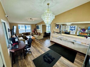 A hotel lobby with a reception desk, a chandelier, a coffee table, and a seating area with a couch and chairs. - Knights Inn Bridgeport Frankenmuth (Bridgeport)