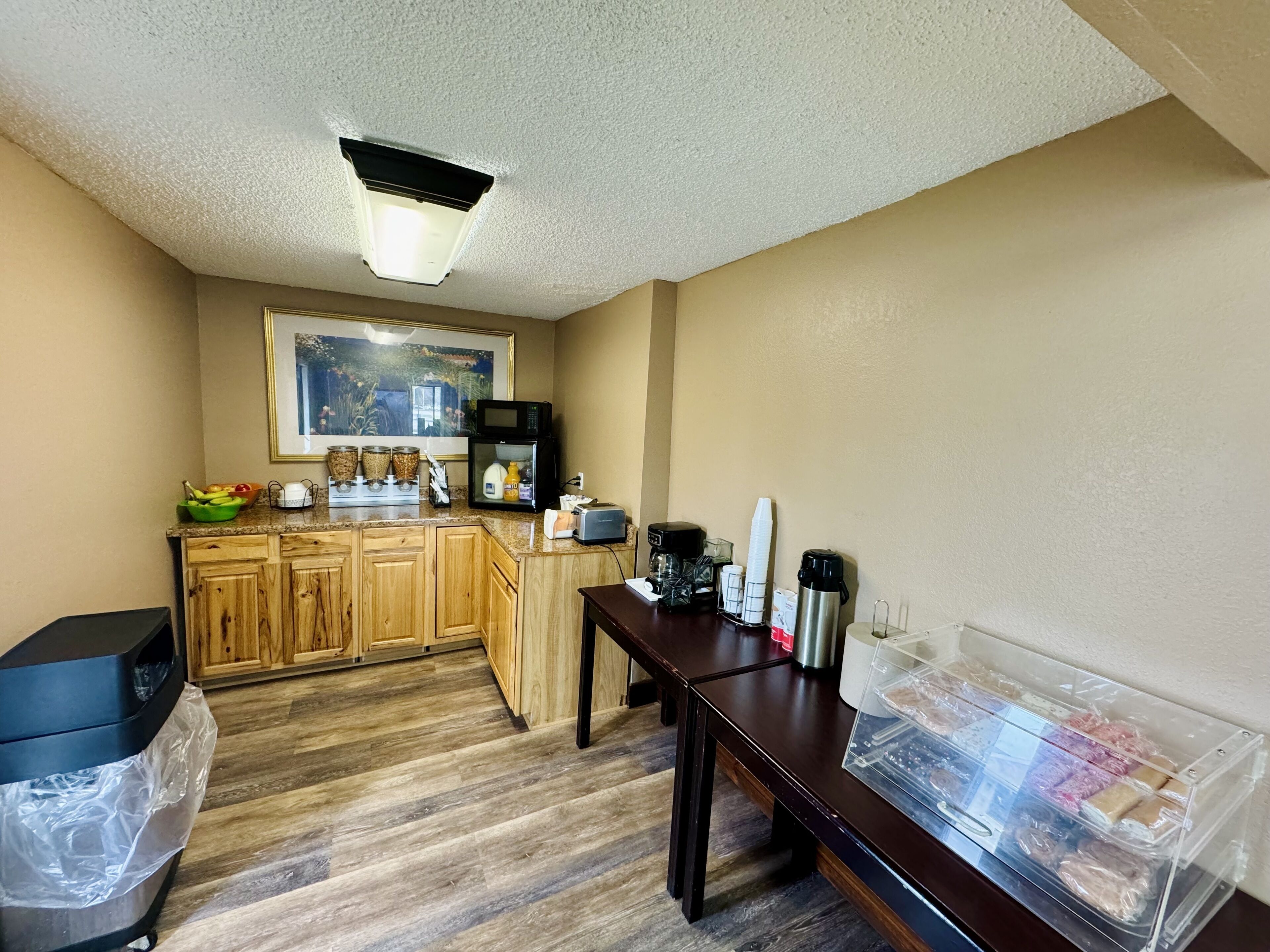 A compact kitchen with wooden cabinets, a microwave, a coffee maker, and a toaster.