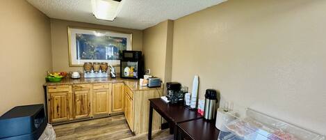 A compact kitchen with wooden cabinets, a microwave, a coffee maker, and a toaster.