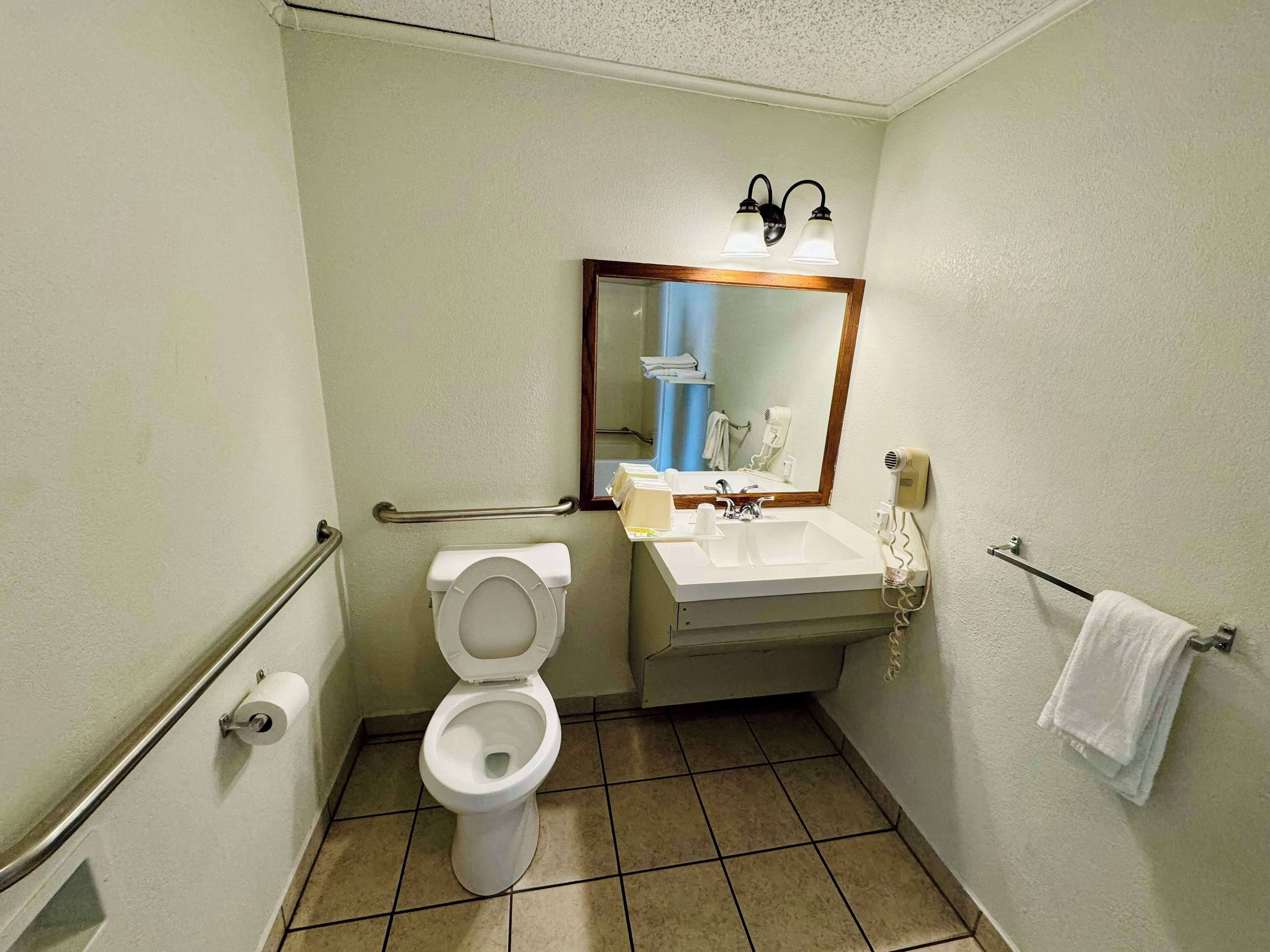 A small bathroom with a toilet, sink, mirror, and towel rack.