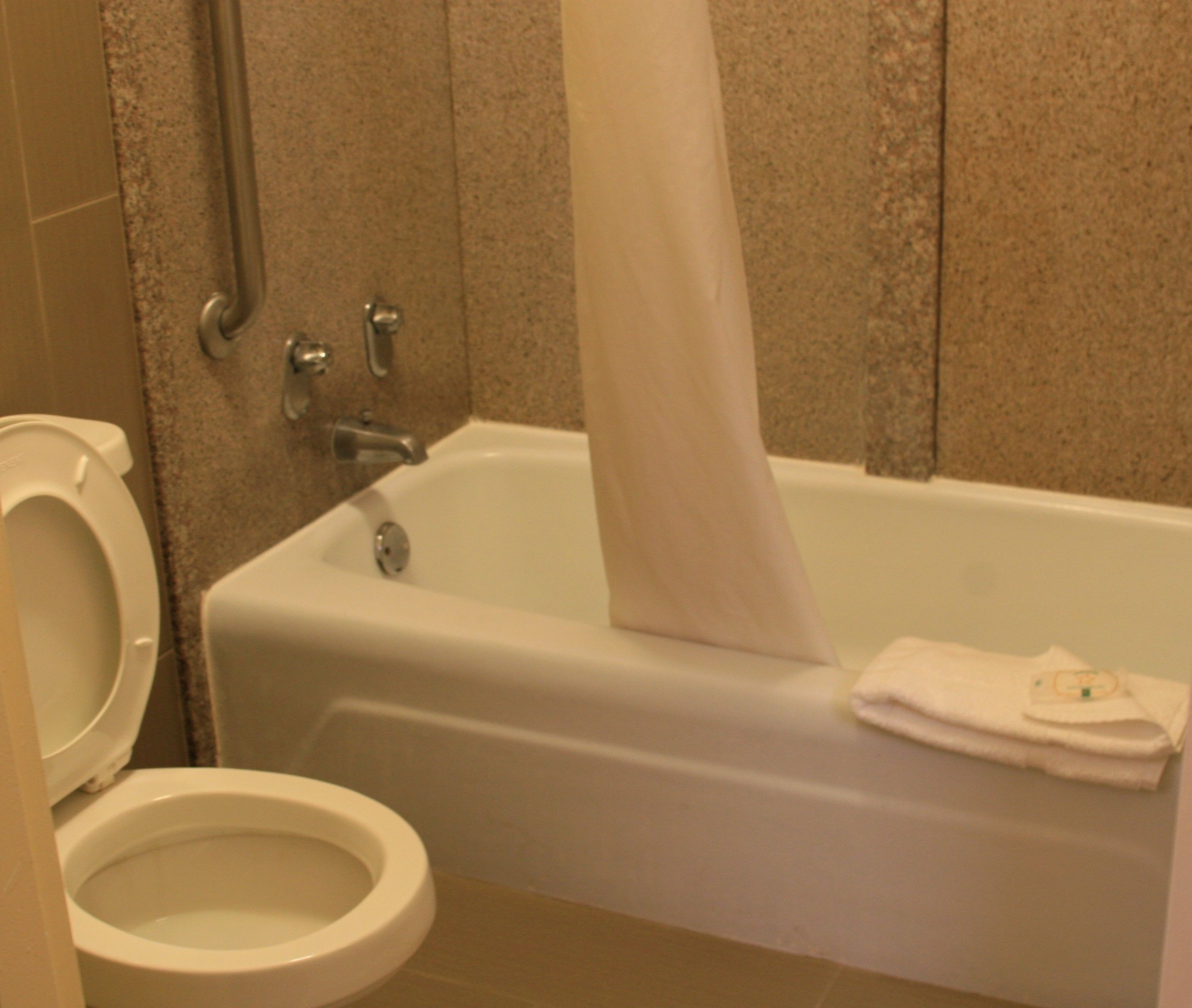 Un baño con bañera, inodoro y cortina de ducha.