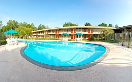 A hotel with a swimming pool, outdoor seating, and a fenced area.