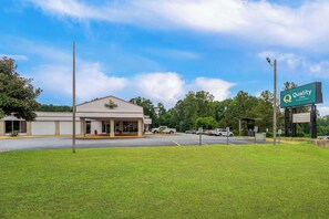 A Quality Inn hotel with a clear sky, a parking lot, and a grassy area in front.