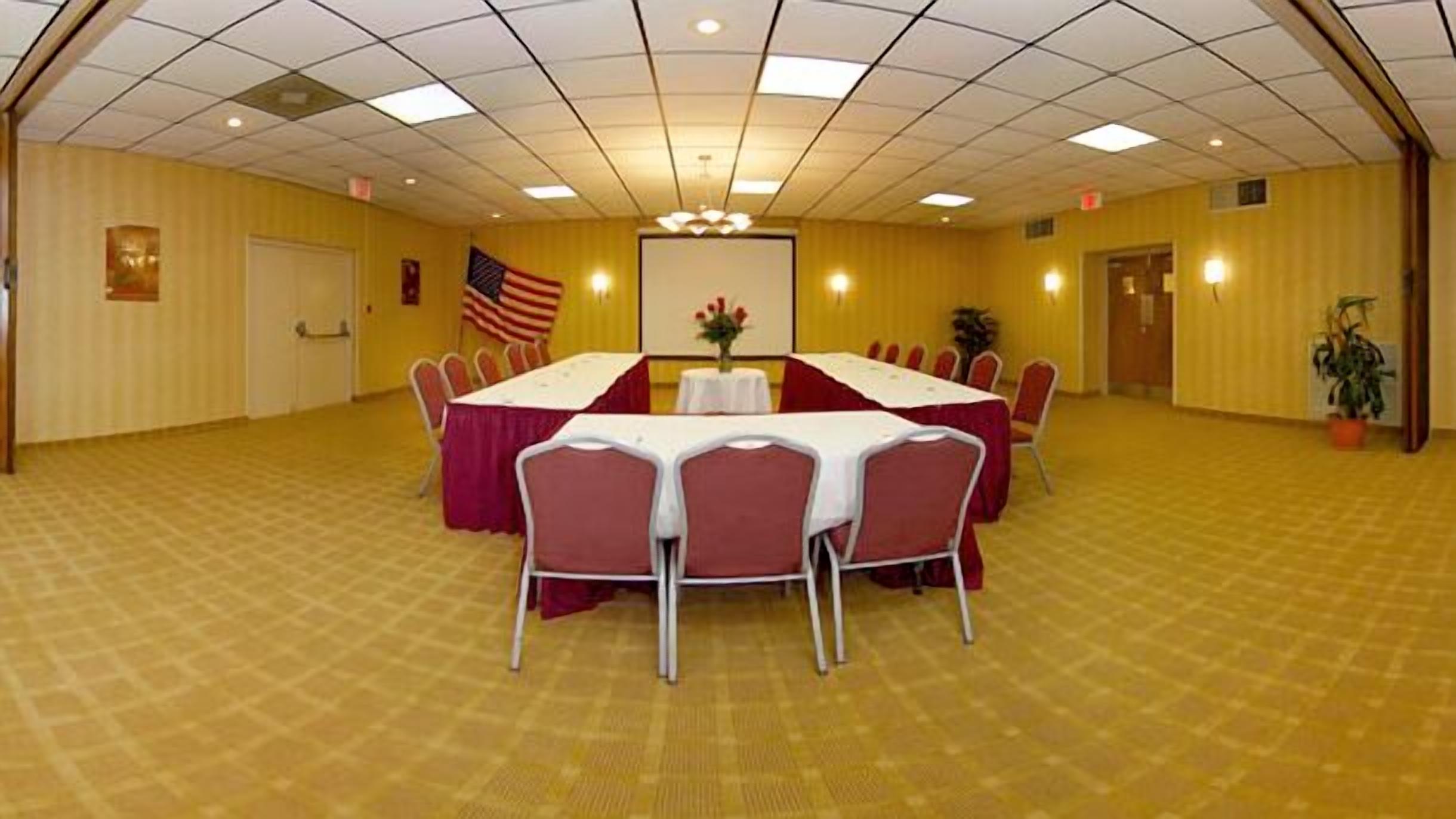 Una sala conferenze con un tavolo grande, sedie e una bandiera americana.