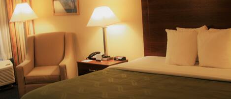 A hotel room with a bed, two bedside lamps, a chair, a nightstand, and a painting on the wall.
