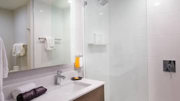 A modern bathroom with a white sink, a mirror, a shower, and a towel rack.
