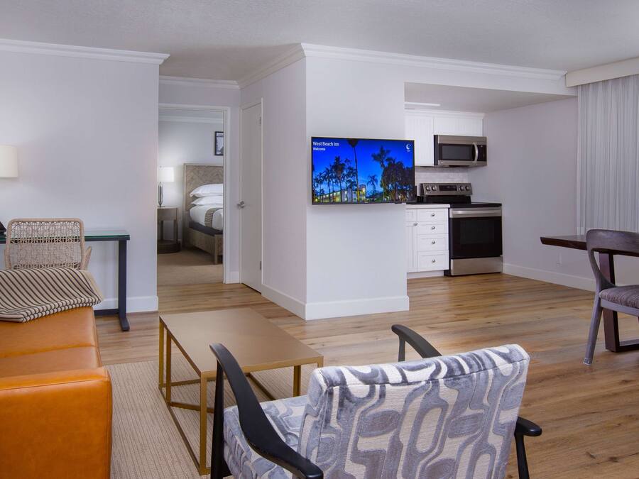 A modern hotel room with a living area, kitchenette, and a bed.
