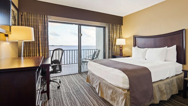 A hotel room with a bed, desk, chair, and a balcony with a view of the sea. - Best Western Fort Myers Waterfront (North Fort Myers)