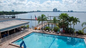 A swimming pool with a dock and palm trees, surrounded by a waterfront view. - Best Western Fort Myers Waterfront (North Fort Myers)
