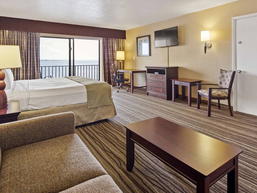 Een hotelkamer met een bed, bureau, stoel, televisie en een deur.