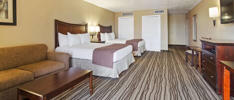 Quarto de hotel com uma cama grande, duas camas menores, um sofá, uma escrivaninha e um armário.