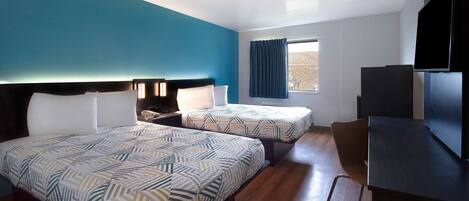 Une chambre d’hôtel avec deux lits, un bureau et une télévision.