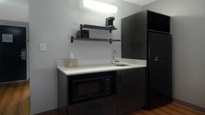 A compact kitchenette with a microwave, a sink, and a black refrigerator. - Motel 6 Merrillville, IN (Merrillville)