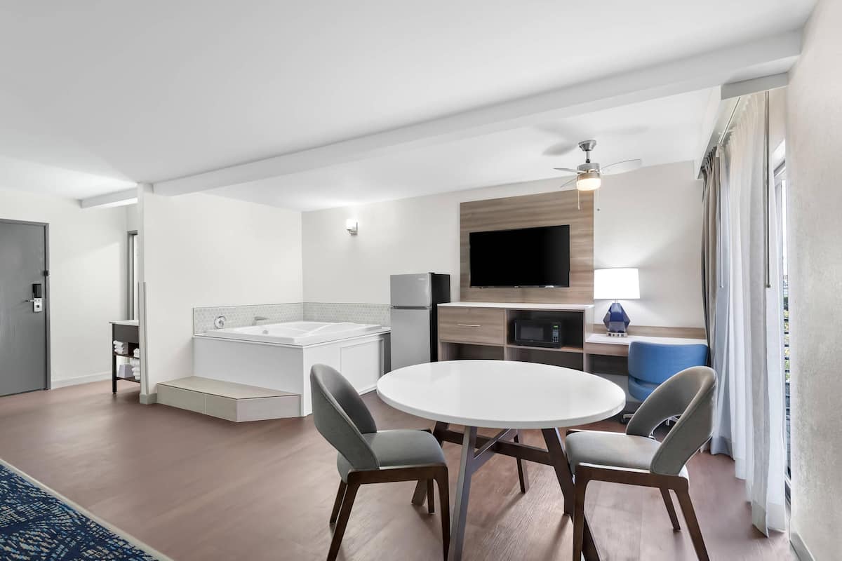 A modern kitchen with a built-in oven, a large flat-screen TV, and a dining area with two chairs.
