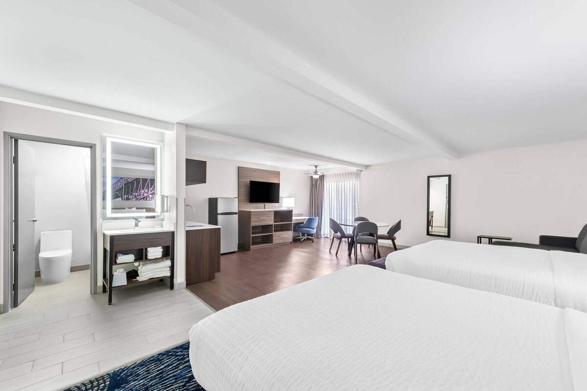 A hotel room with a bed, a desk, a chair, a TV, and a bathroom.