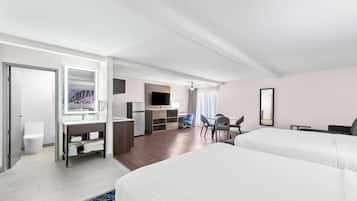 A modern hotel room with a large bed, a desk with a chair, a TV, and a bathroom with a toilet and sink.