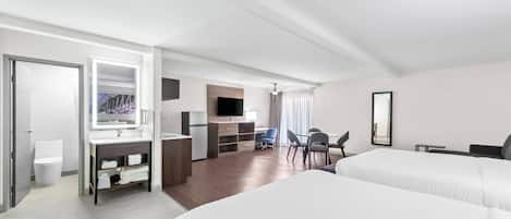 A modern hotel room with a large bed, a desk with a chair, a TV, and a bathroom with a toilet and sink.