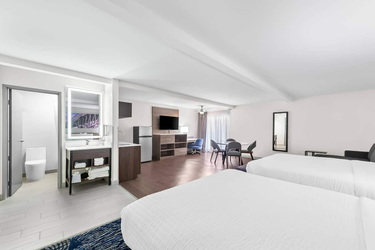 A hotel room with a bed, a desk, a chair, a TV, and a bathroom.