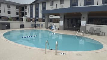 Una piscina al aire libre, sillones reclinables de piscina