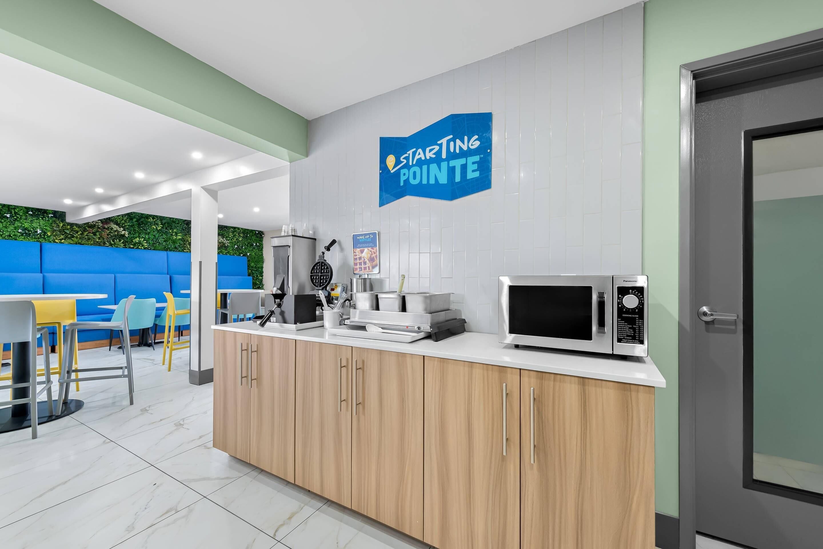 A modern kitchen with a microwave, coffee maker, and a blue sign that reads "Starting Pointe".