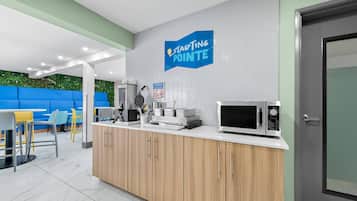 A modern kitchen with a microwave, coffee maker, and a blue sign that reads "Starting Pointe".