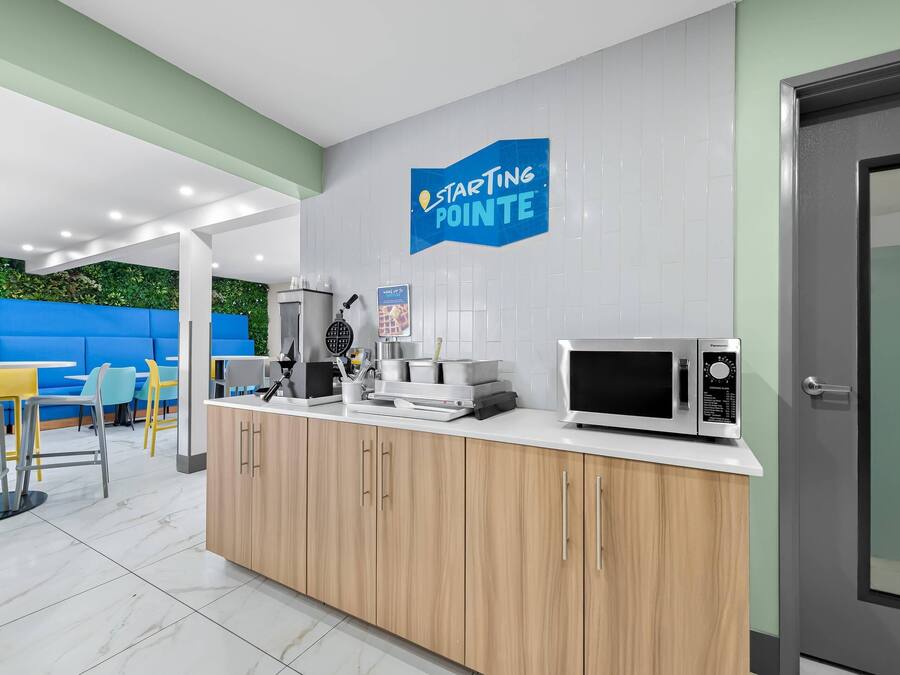 A modern kitchen with a microwave, coffee maker, and a blue sign that reads "Starting Pointe".