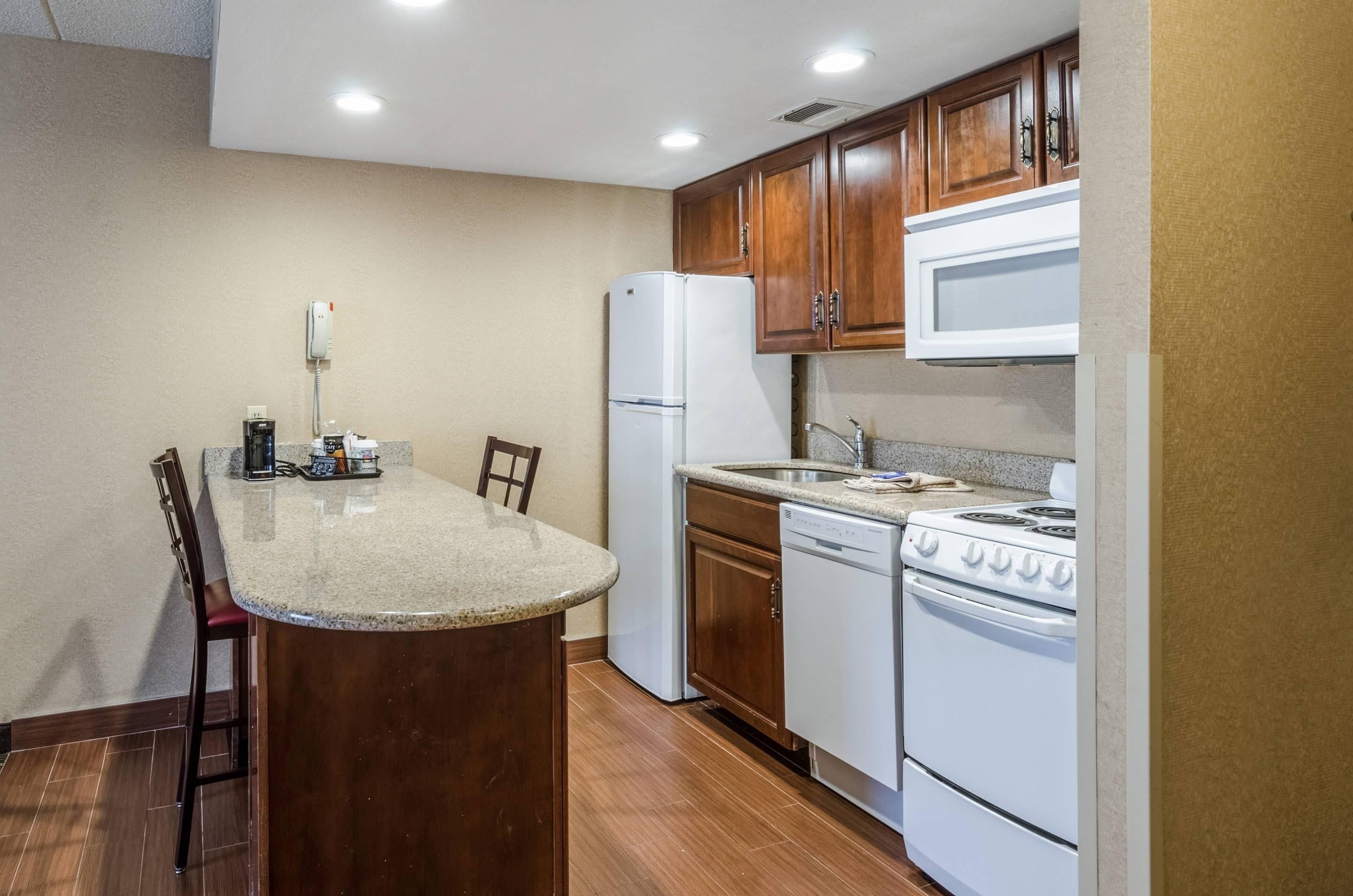 A kitchen with a central island, wooden cabinets, a refrigerator, a stove, and a dishwasher.