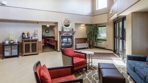 A spacious living area with a fireplace, seating, and a view through large windows. - Comfort Inn & Suites West Springfield (West Springfield)