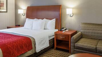 Een hotelkamer met een groot bed, twee nachtkastjes, een stoel en een kleine tafel.