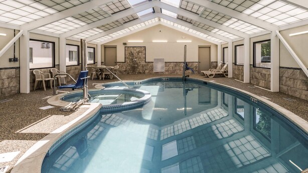 An indoor swimming pool with a skylight roof, lounge chairs, and a hot tub. - Comfort Inn & Suites West Springfield (West Springfield)