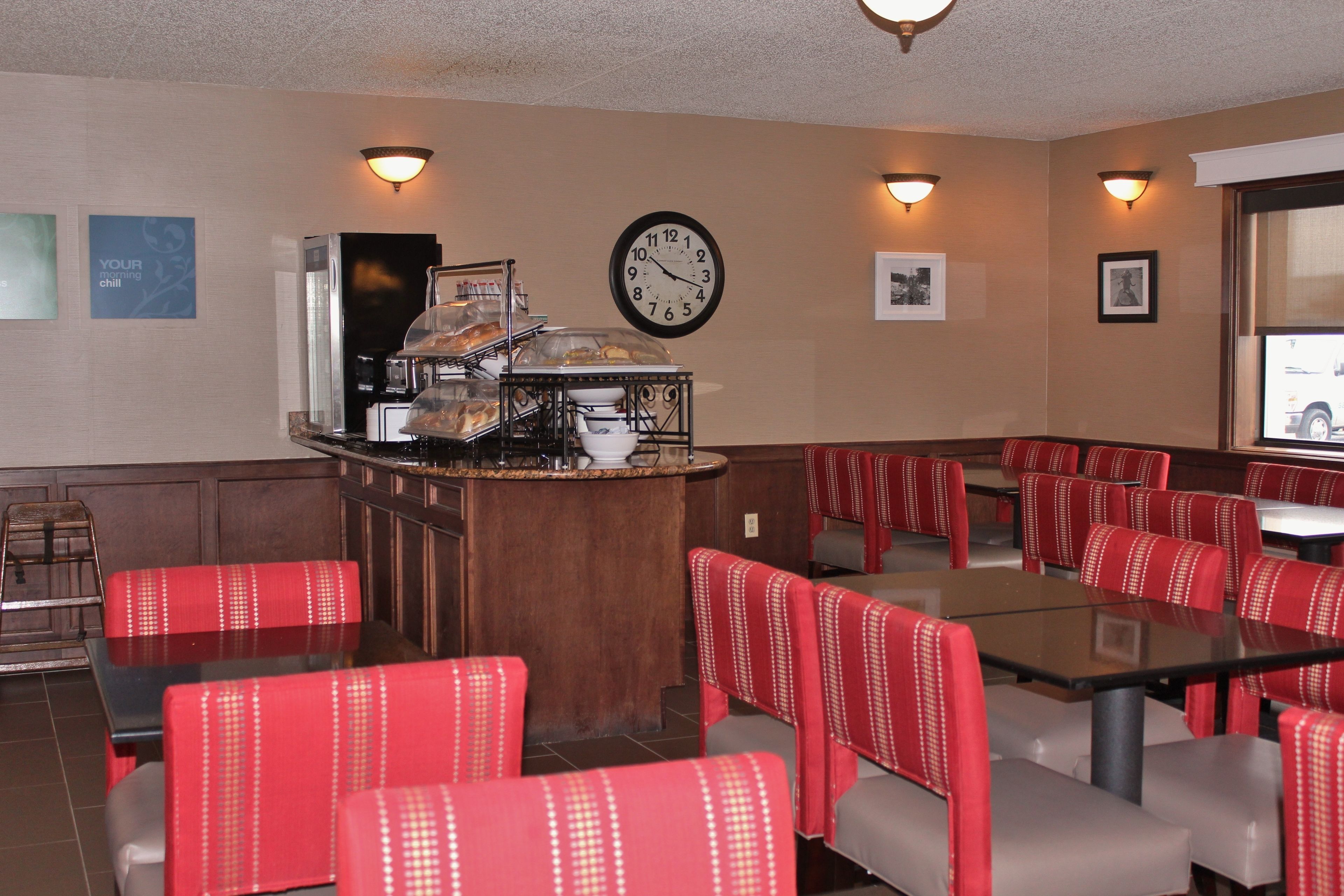 A restaurant with red upholstered booths, a buffet counter, and a wall clock.