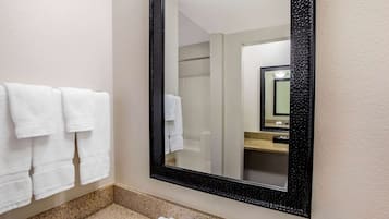 A bathroom with a large mirror, a sink, and towels hanging on the wall.