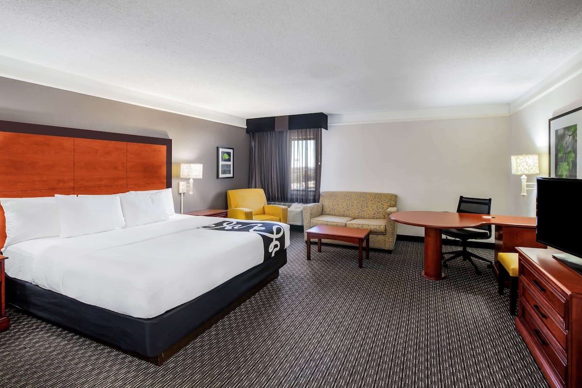 Een hotelkamer met een groot bed, een bureau, een stoel, een bank en een televisie.