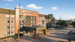 Un hotel La Quinta con un diseño moderno, que presenta un llamativo logo de sol, varios pisos y un estacionamiento.