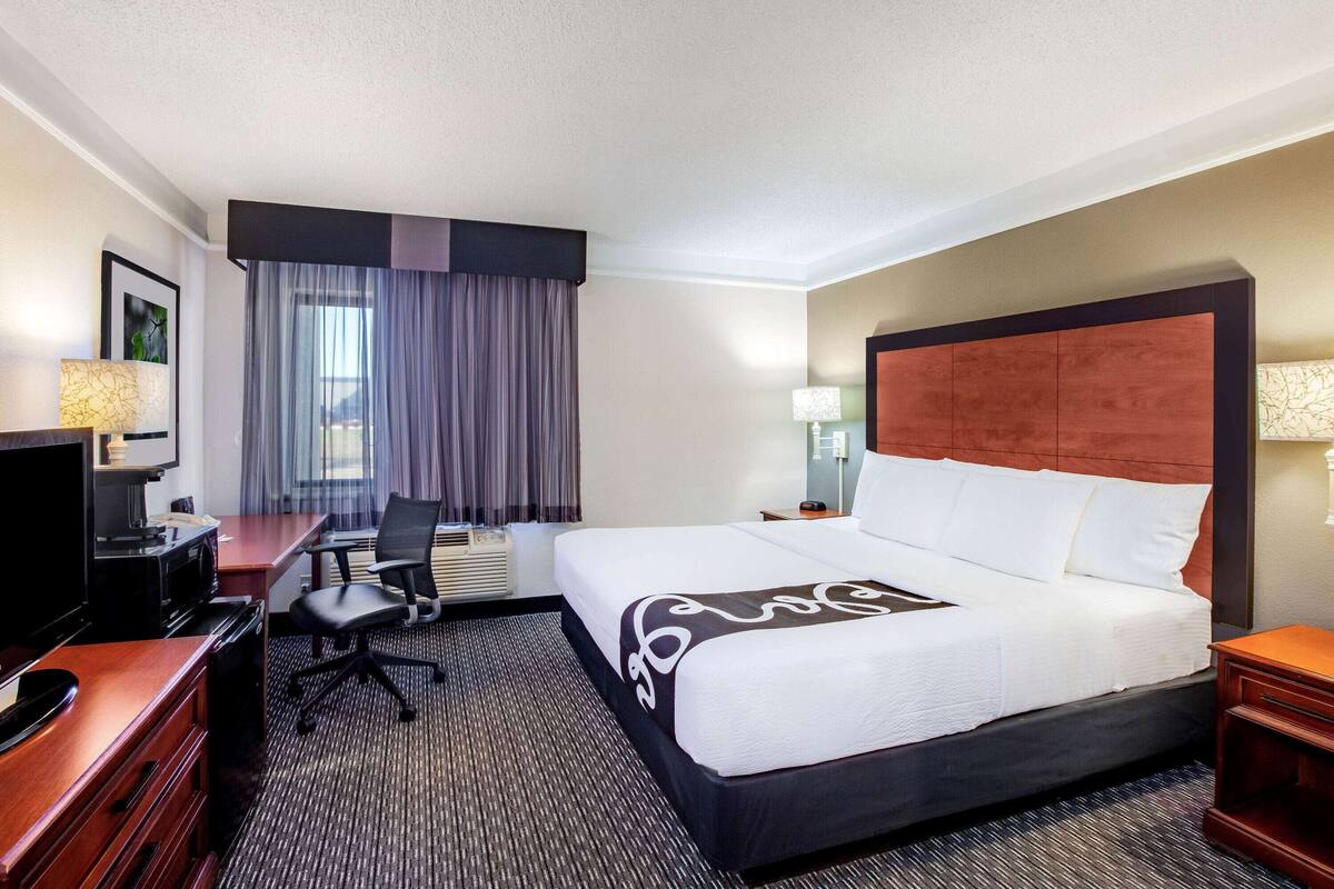 Een hotelkamer met een groot bed, een bureau met een computer, een stoel en een televisie.