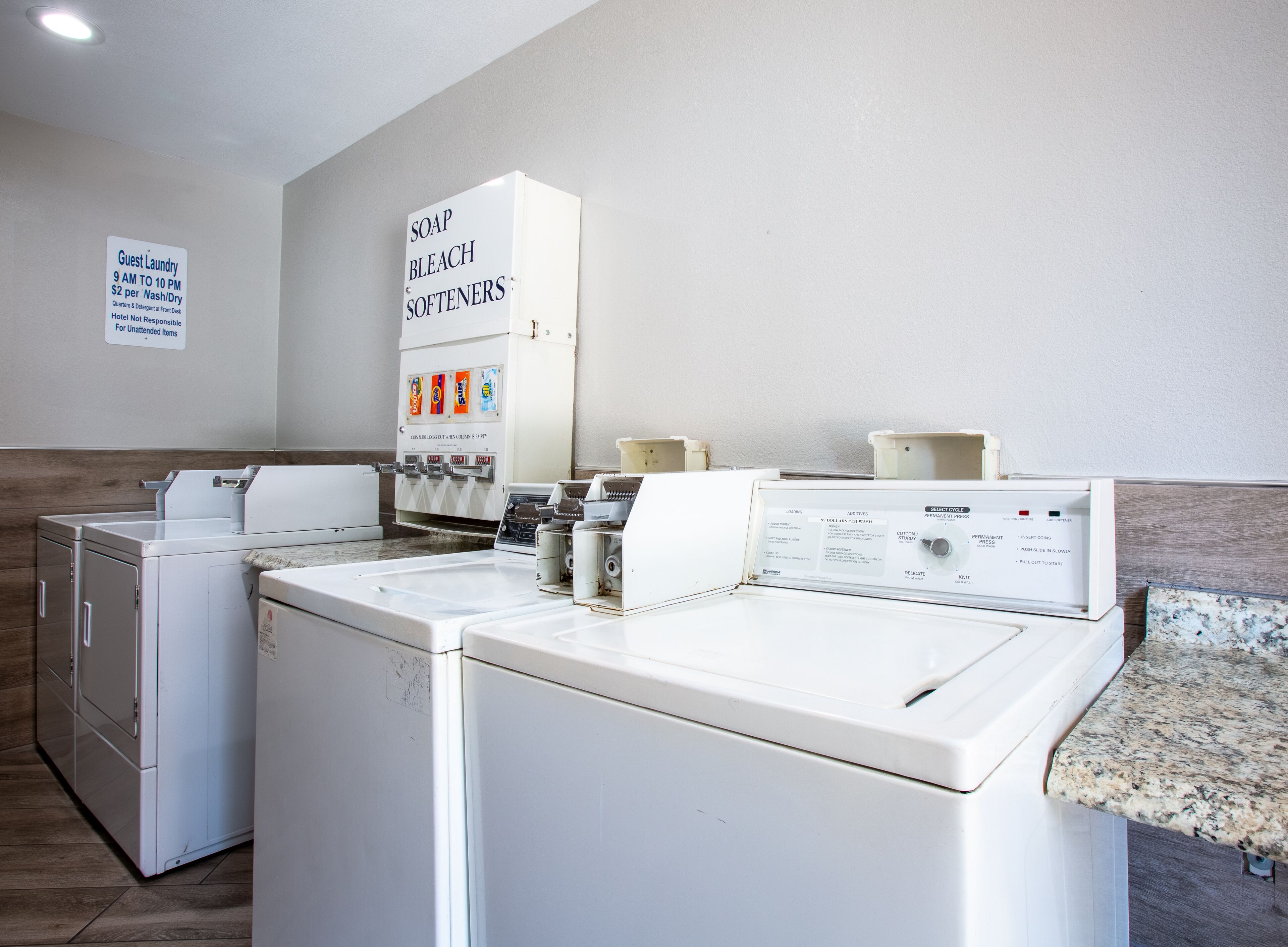 A laundry area with washers and dryers, a soap and bleach station, and a sign for guest laundry hours.