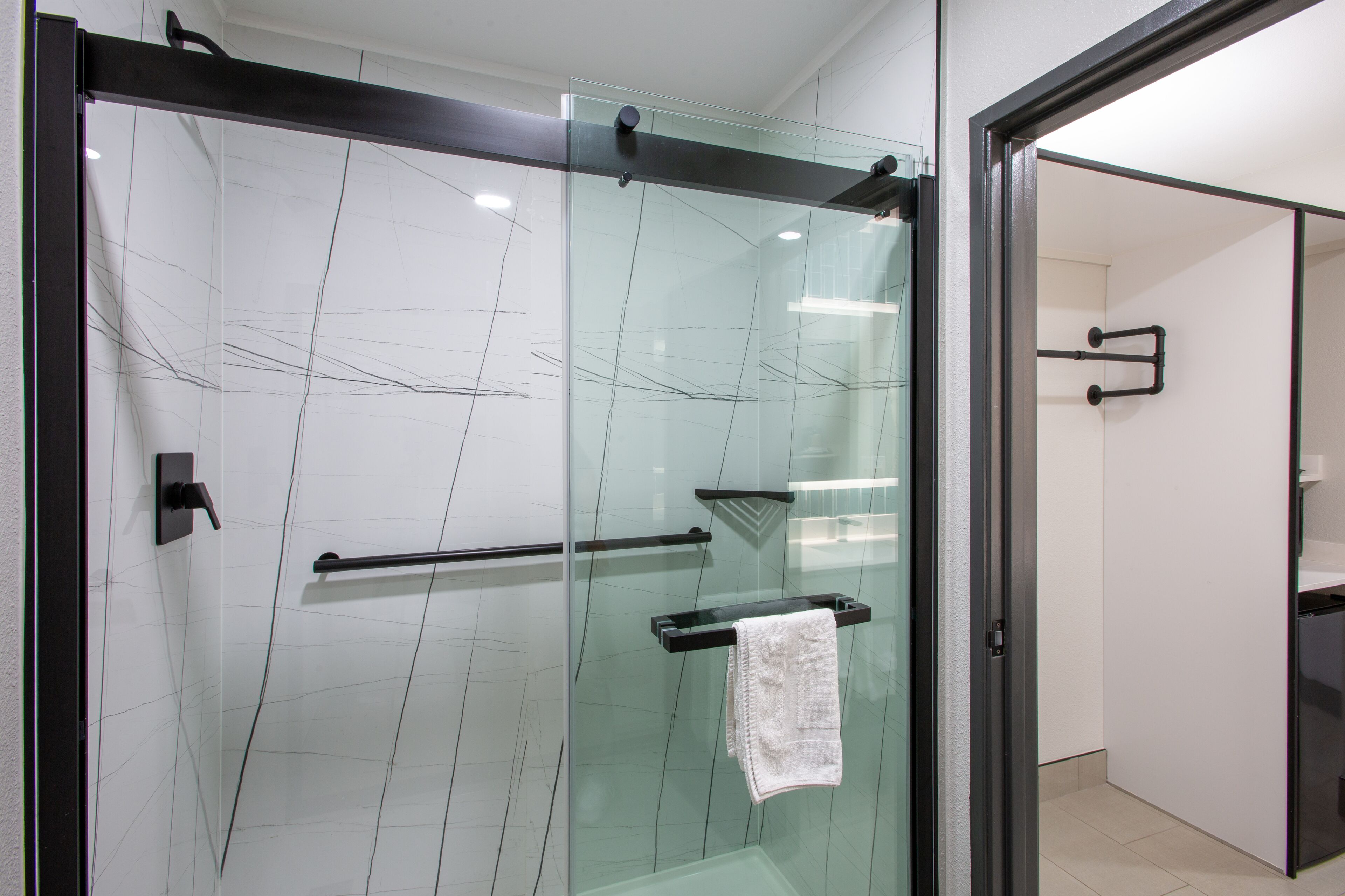 A glass-enclosed shower with a towel rack and a glass door.