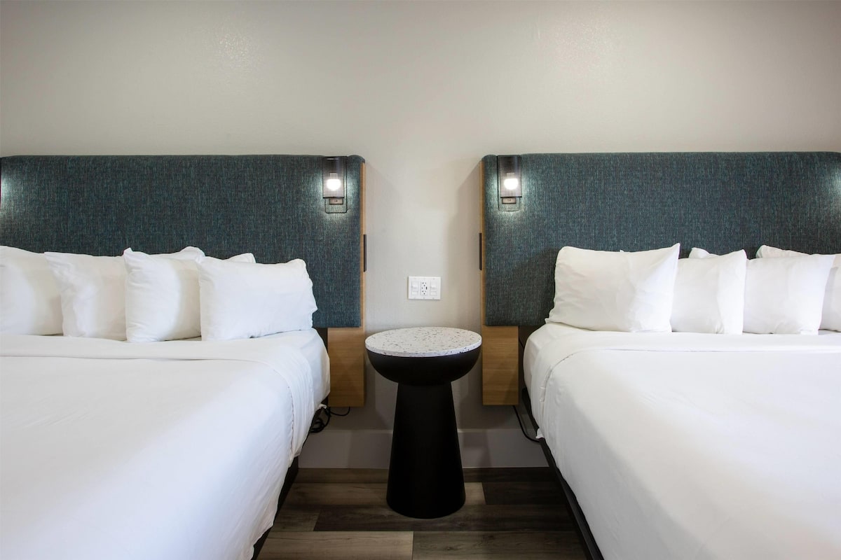 Ein Hotelzimmer mit zwei Betten, einem runden Tisch und Wandleuchten.