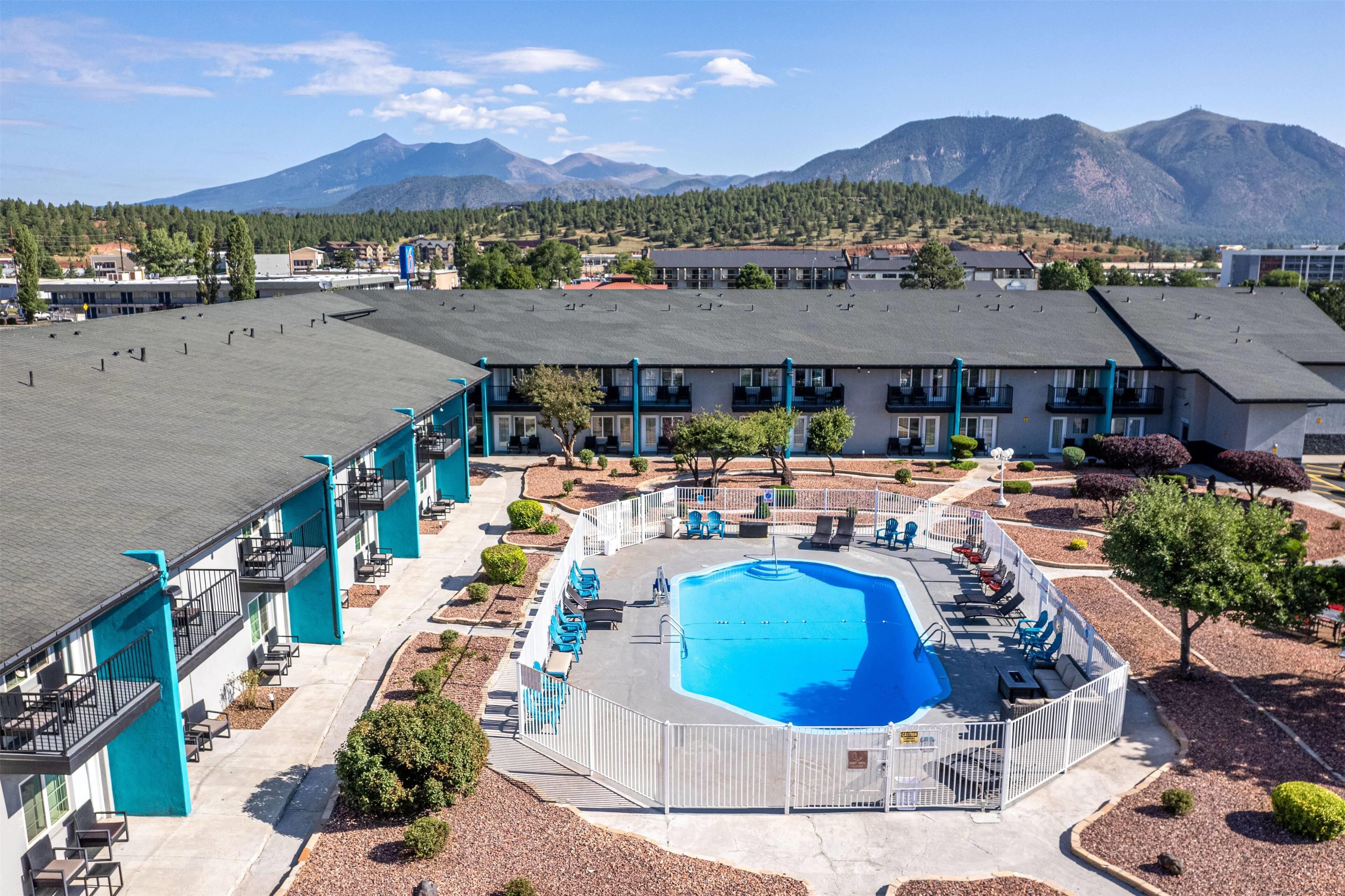Hotel med swimmingpool omgivet af liggestole og et bjerg i baggrunden.