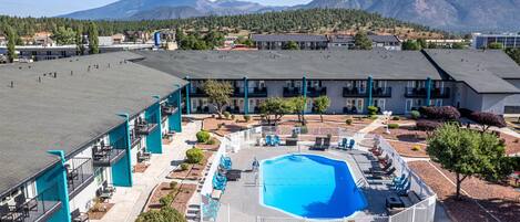Hotel med swimmingpool omgivet af liggestole og et bjerg i baggrunden.