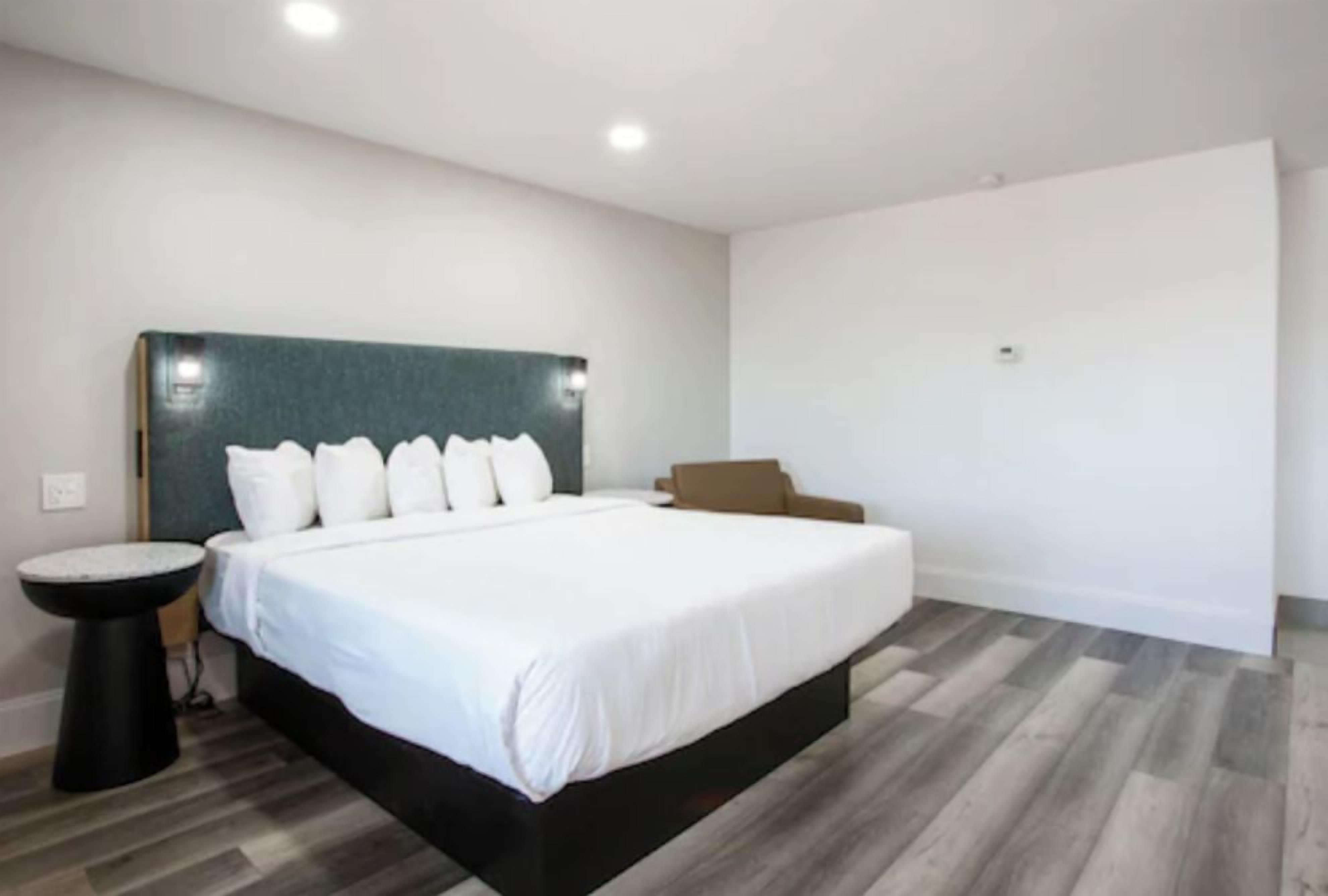 A modern bedroom with a large bed, a round side table, and a headboard.
