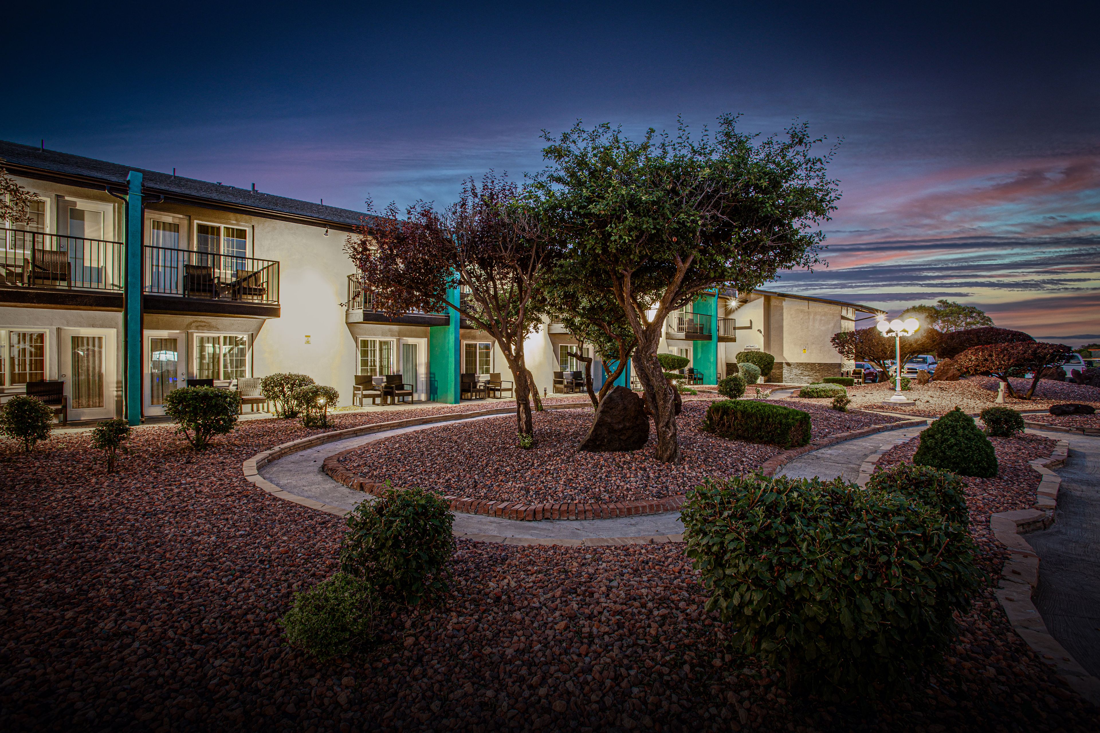 A hotel courtyard with a tree, seating area, and a building with balconies.