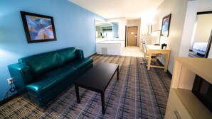 Et hotelværelse med en grøn sofa, et lille bord, et skrivebord og en seng.
