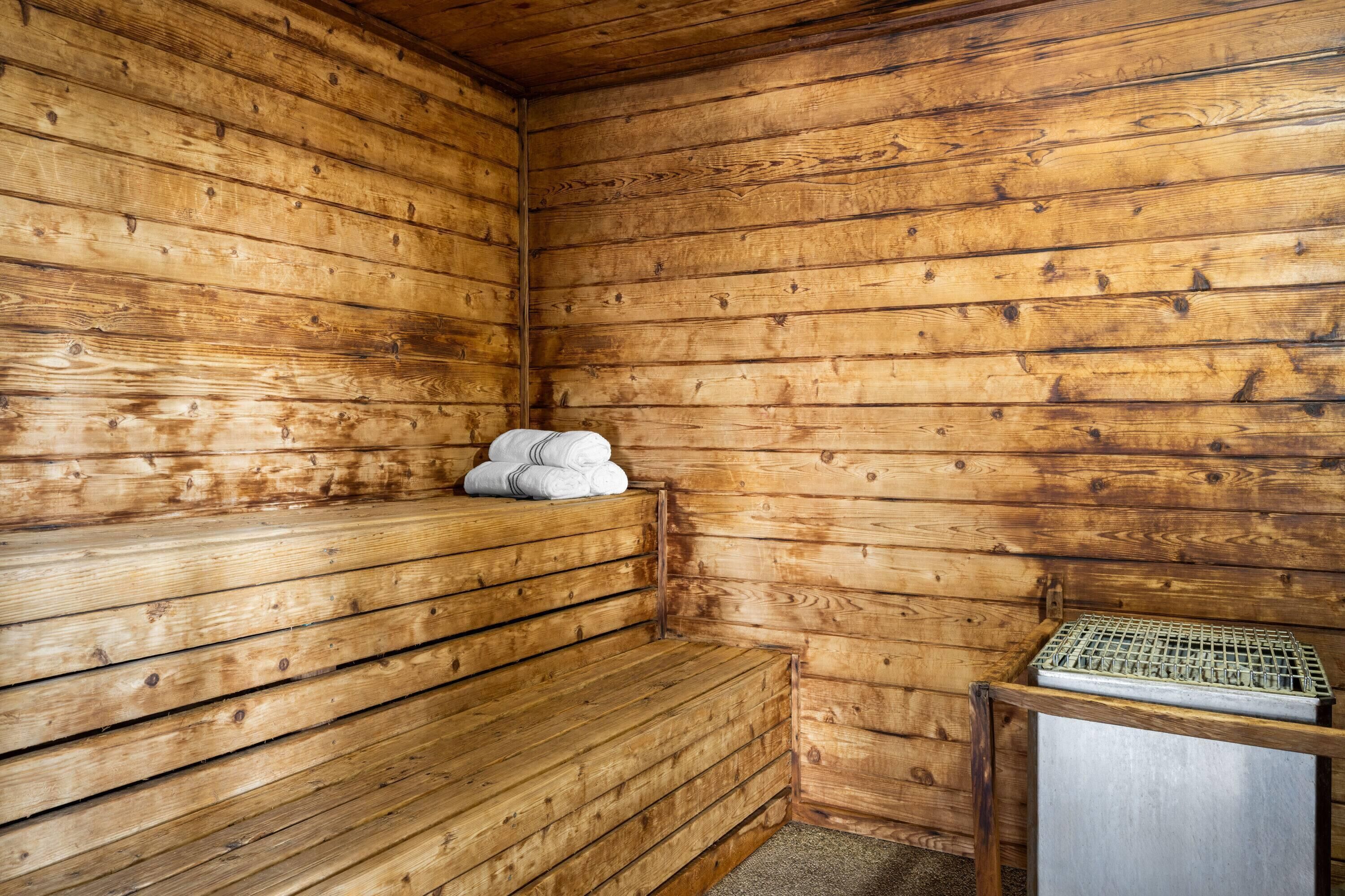Una sauna de madera con bancos y una bandeja metálica.
