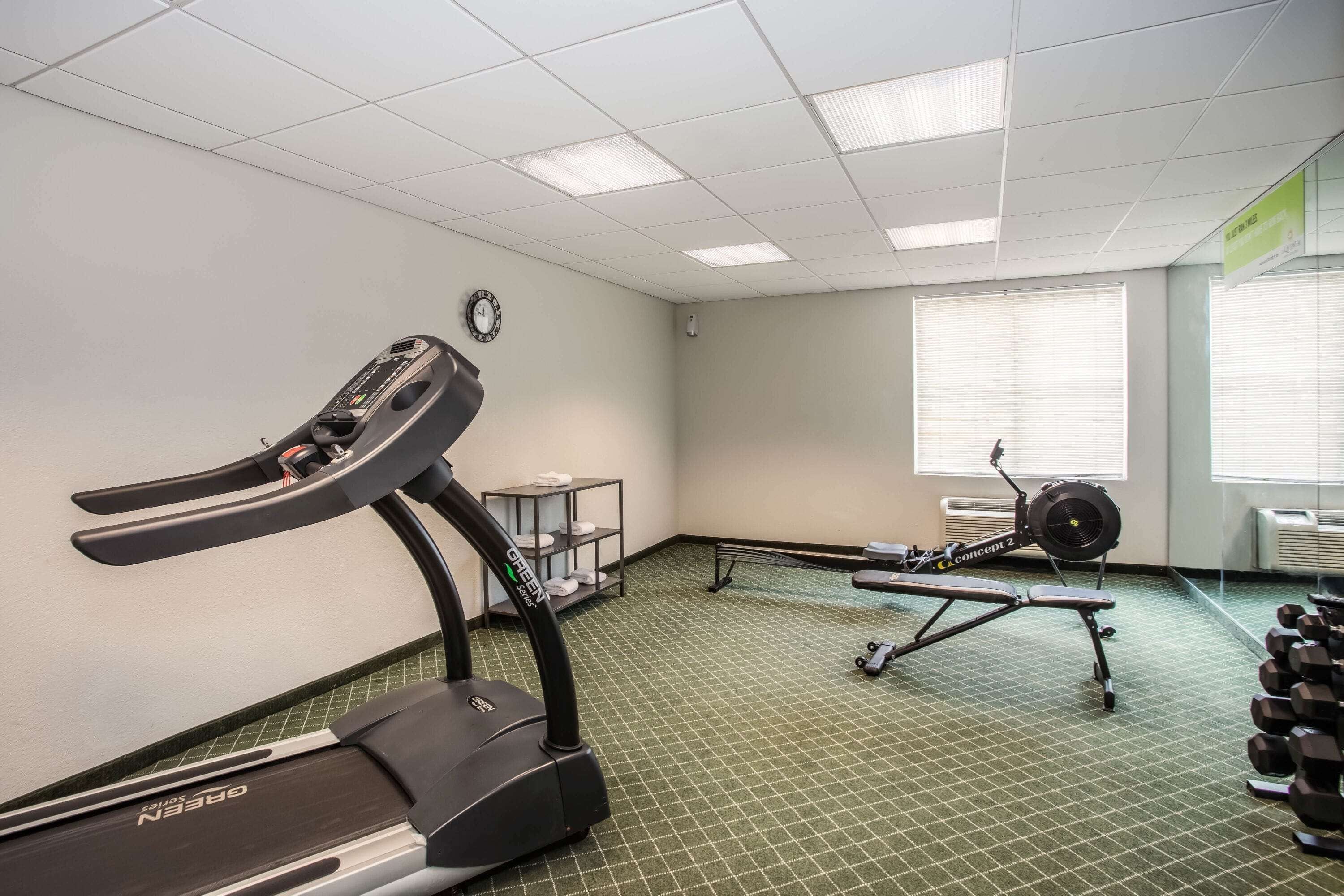 Una palestra con tapis roulant, vogatore e manubri.
