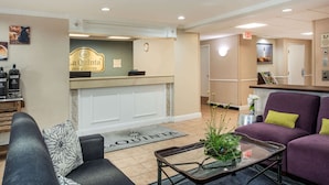 A hotel lobby with a reception desk, seating area, and a coffee station.