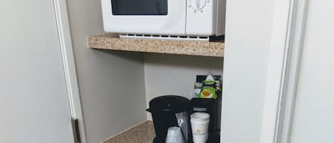 A compact kitchenette with a microwave, coffee maker, and a mini-fridge.