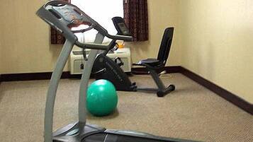 A fitness room with a treadmill, a stationary bike, and a green exercise ball.